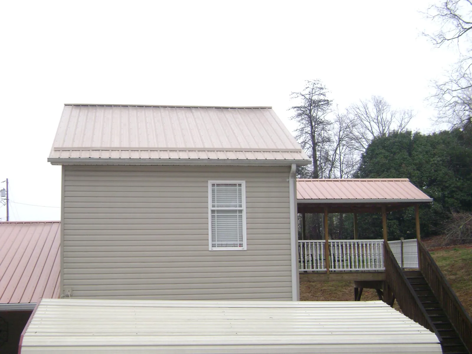 Tan metal roofs on a two story addition and attached porch, from a Roof Replacement job in Bliss