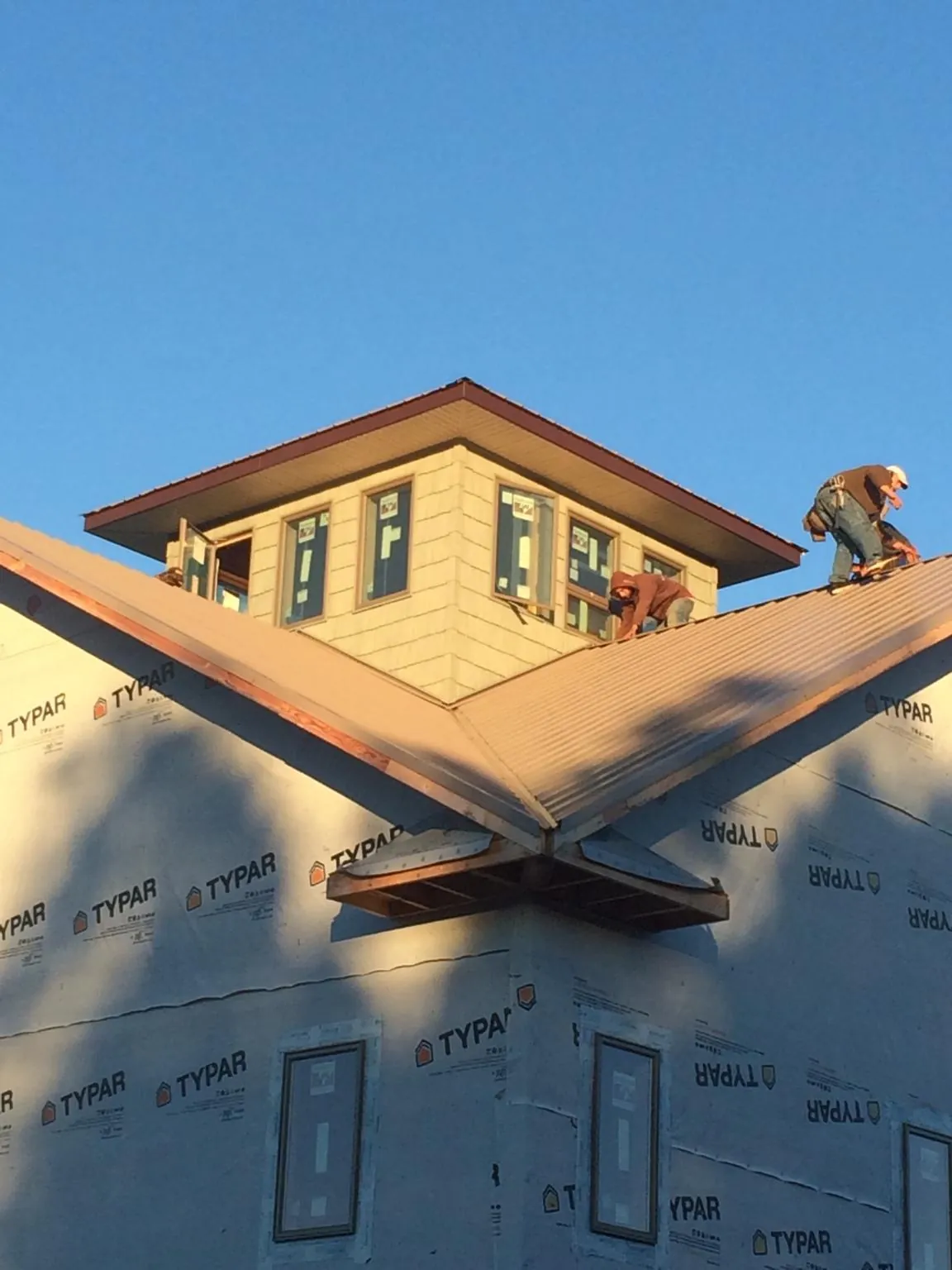 Roofers working around a rooftop cupola on a new metal roof at sunset — Roof Waterproofing in Bliss by Roofing Brothers